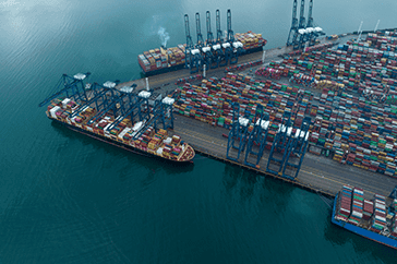 Aerial view of a busy Portuguese container port with cargo ships and cranes in Centro Region, highlighting maritime logistics and the need for green port infrastructure in Portugal