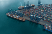 Aerial view of a busy Portuguese container port with cargo ships and cranes in Centro Region, highlighting maritime logistics and the need for green port infrastructure in Portugal